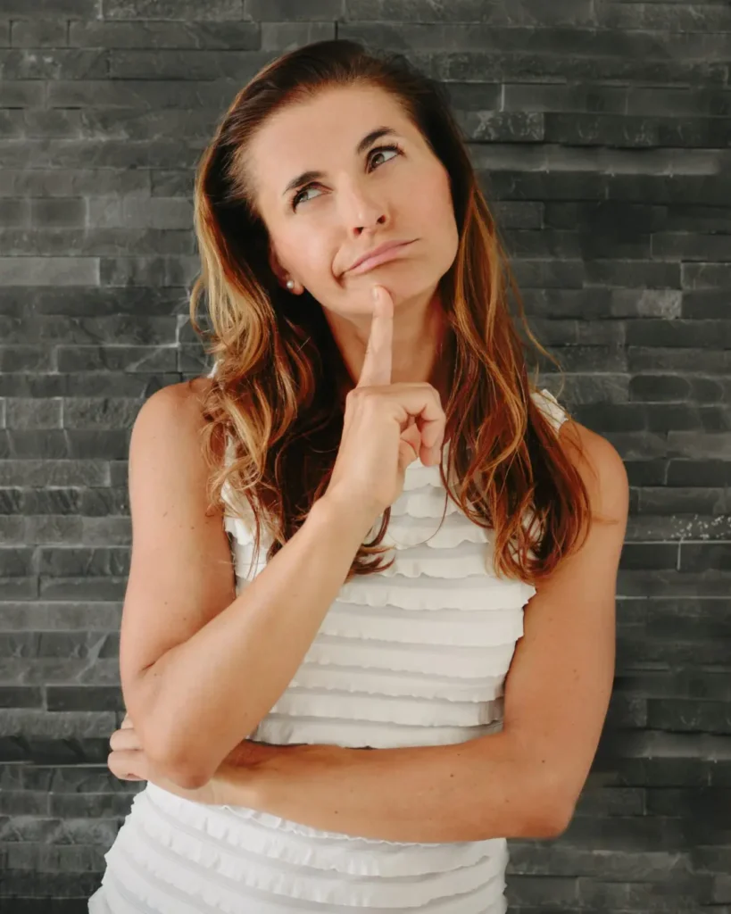 %functional medicine nutritionist% %Blanka Campbell% Blanka Campbell smiling thoughtfully in front of a dark background, wearing a white sleeveless top.