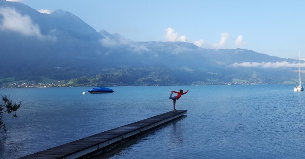 Woman practicing yoga on a pier by a mountain lake in Switzerland